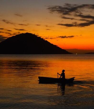 Fisherman on boat at sunset in lake