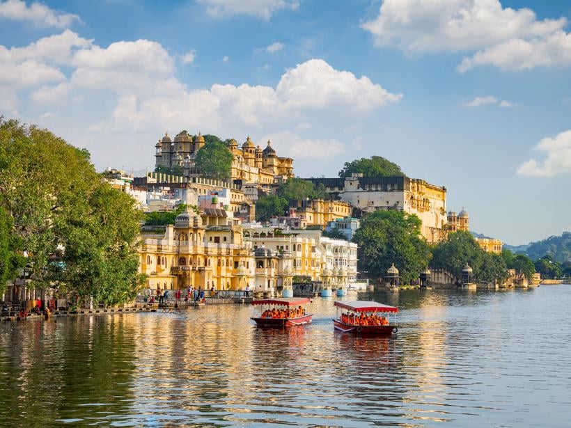 view of an opulent palace alongside a clear lake in Udaipur, India