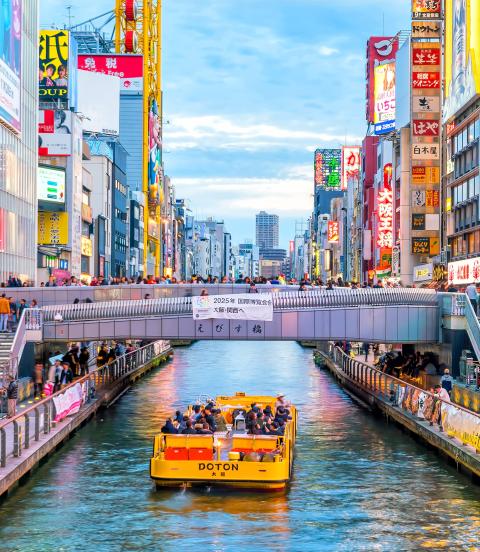 Boat floating down canal on Dotonbori shopping street, a famous destination for traveling and shopping in Osaka