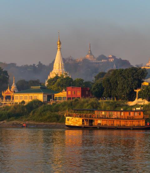 Landscape of Myanmar from the river just after sunrise. Warm colors, lots of pagoda's and a steamboat