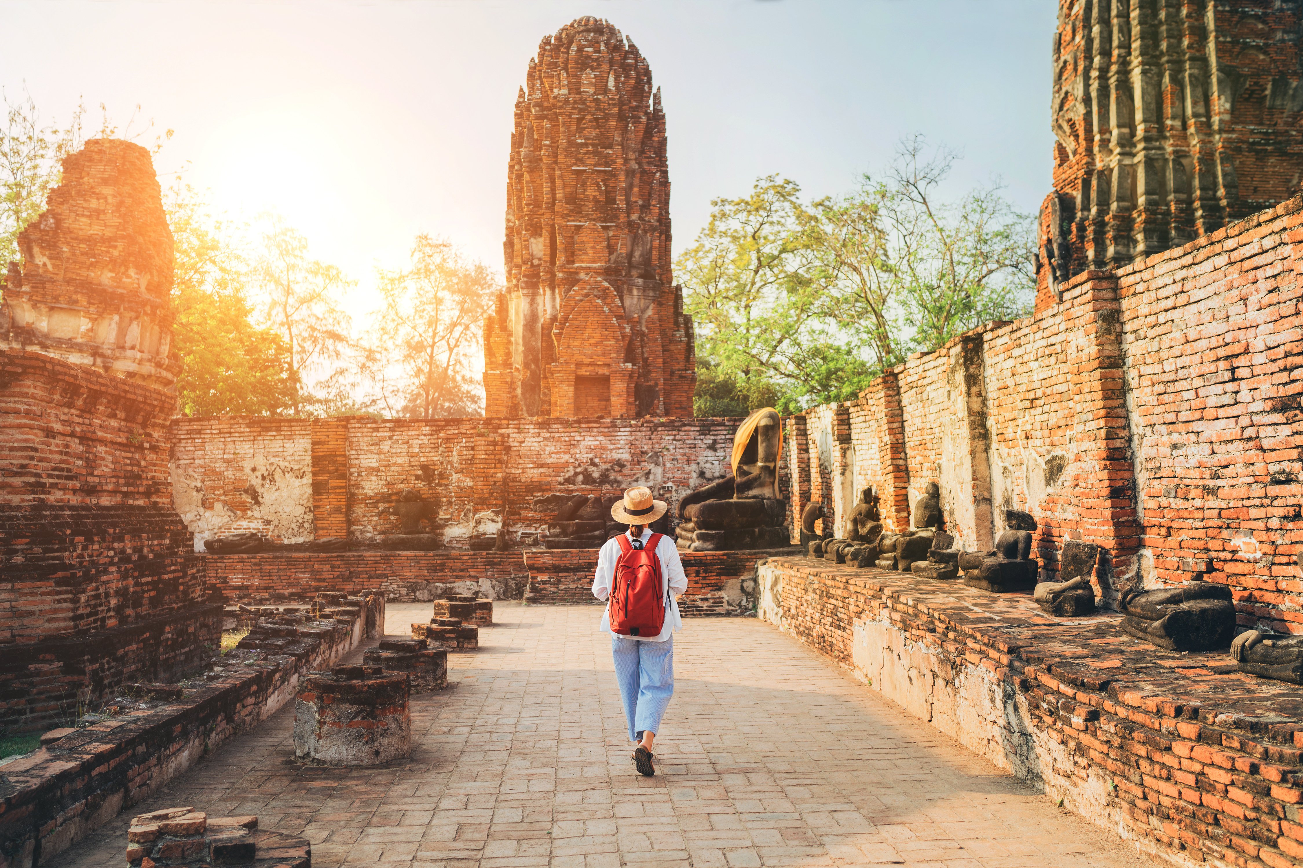 Woman walks through Ayutthaya Wat Phra Ram ancient ruins streets in Thailand