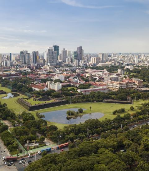 Aerial of Intramuros, an old historic walled city, surrounded by golf courses, and Manila skyline in background