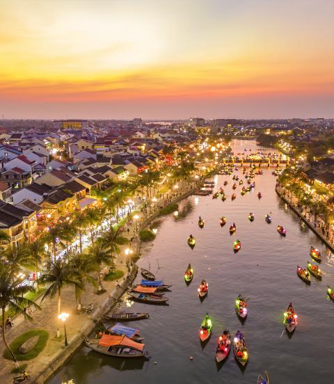 Hoi An at dusk with boats cruising on Thu Bon River with lanterns