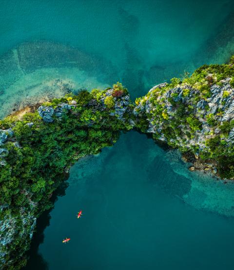 Drone view on rocks and canoes floating on turquoise water