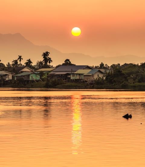 Sunset along the river  with a local village and mountains in the background