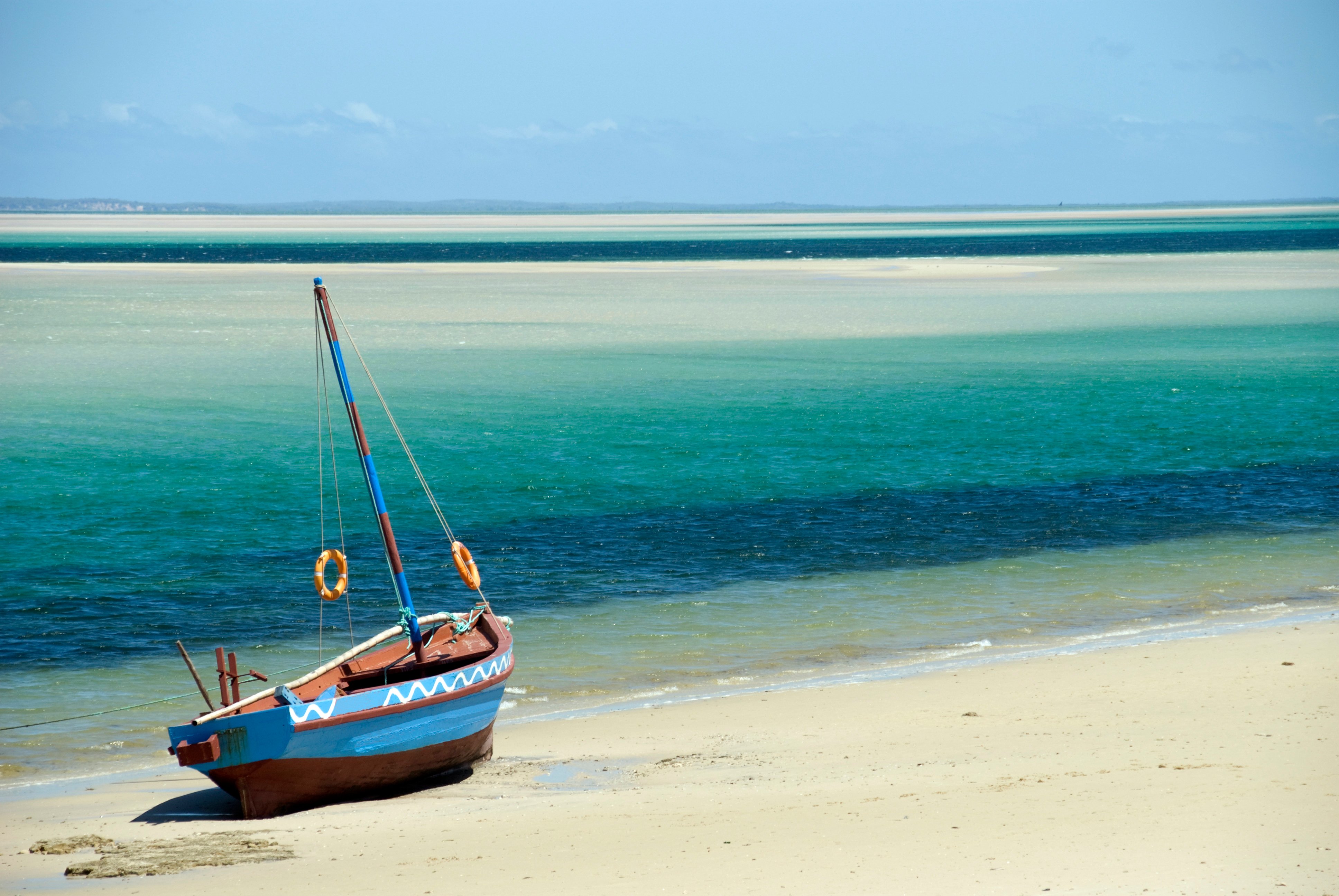 A Dhow (boat) sitting at the water's edge on a beach