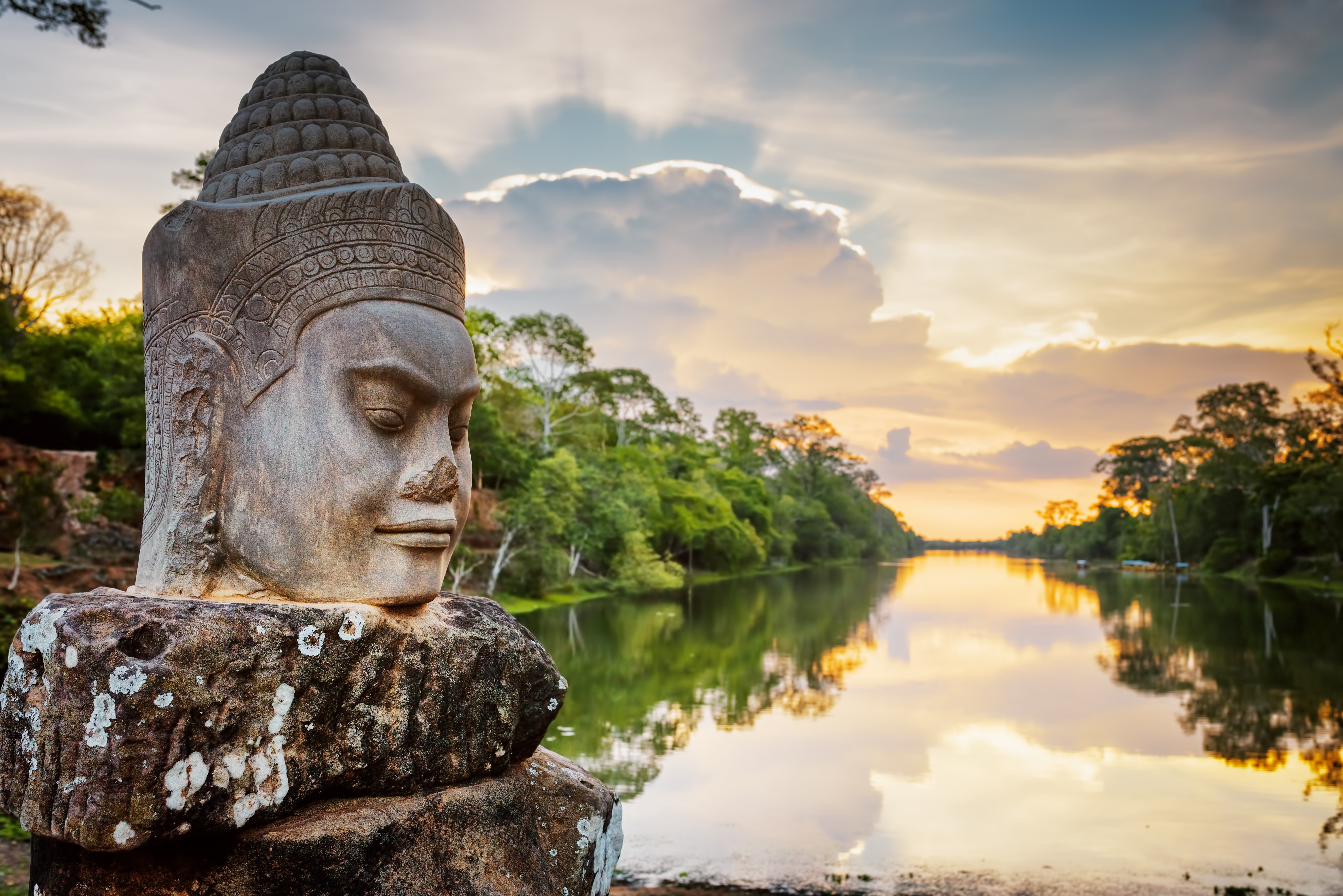 Stone face Asura over moat on causeway near South Gate of Angkor Thom in Siem Reap, Cambodia